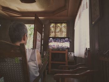 Rear view of man standing on table at home