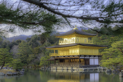 Built structure by lake and building against trees