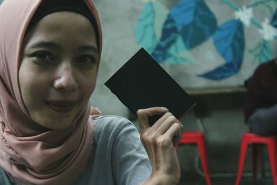 Close-up portrait of young man holding camera