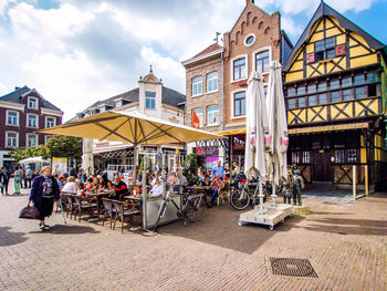 People at sidewalk cafe in city against sky