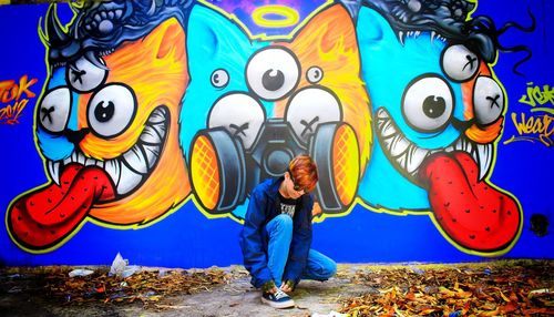 Full length of man standing against graffiti wall