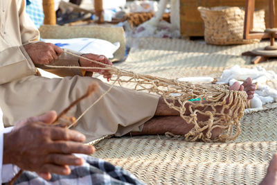 Old man is knitting traditional fishing net, hands in frame