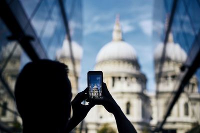 Rear view of man photographing through smart phone