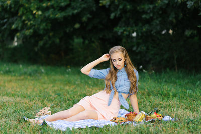 Young woman is resting while sitting on a picnic blanket person