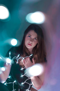 Portrait of young woman holding illuminated lights