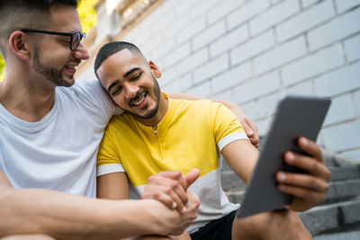 Gay men using digital tablet while siting on staircase