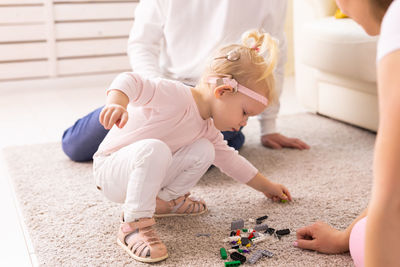 High angle view of siblings playing with toy on bed at home