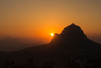 Scenic view of silhouette mountains against orange sky