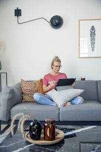 Woman on sofa using digital tablet