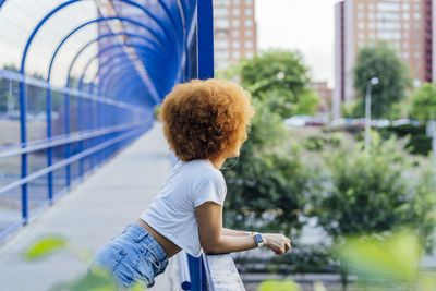 Woman with afro hair leaning on a bridge
