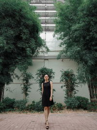 Full length portrait of woman standing against trees