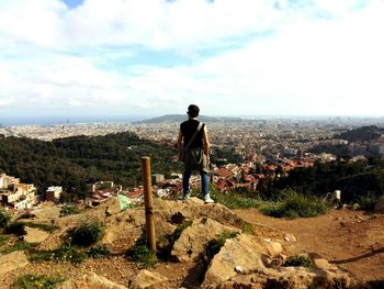 Rear view of man standing on landscape against sky