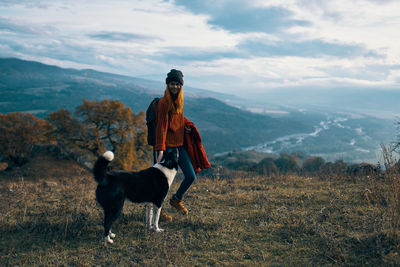 Man with dog on mountain against sky