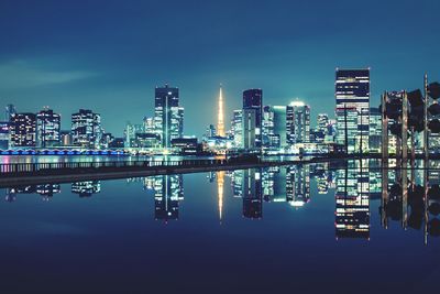 Reflections of illuminated buildings against sky at night