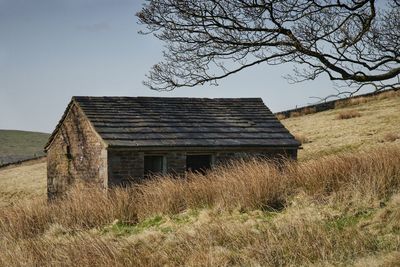 Exterior of abandoned building on field against sky