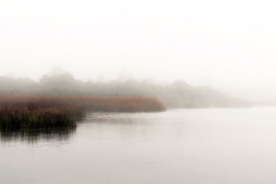 Scenic view of lake against sky during foggy weather