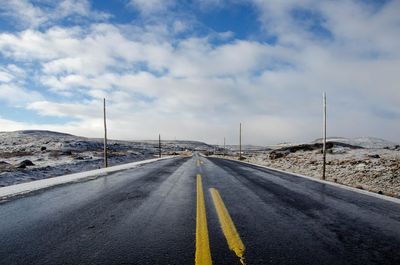 Empty road against cloudy sky