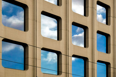 Reflection of cloudy sky on window glass of building