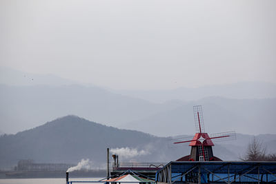 Traditional windmill by mountain against sky