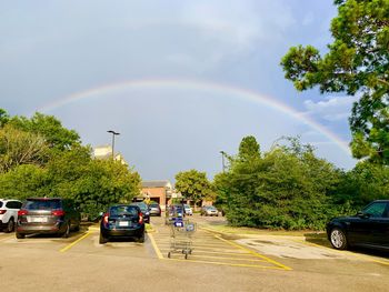 Cars on road against rainbow in city