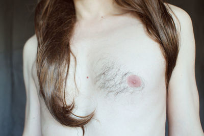 Midsection of shirtless man with long hair standing