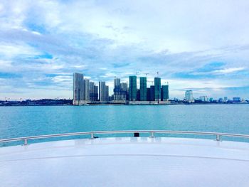 Sea by cityscape against sky