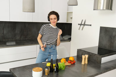 Side view of young woman using mobile phone while standing at home