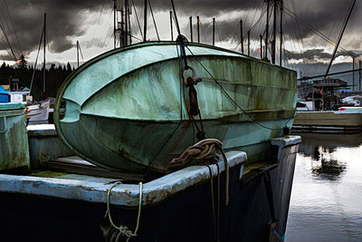 Fishing boat moored at harbor against sky