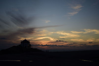 Capela do senhor da pedra at silhouette beach during sunset