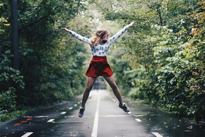 Full length of woman jumping over road