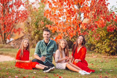 Rear view of people sitting on autumn leaves