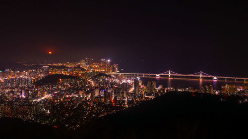 Illuminated cityscape against sky at night