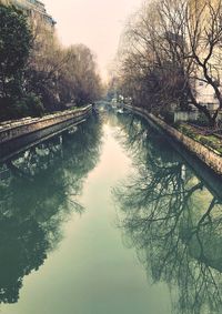 Bridge over river amidst trees against sky
