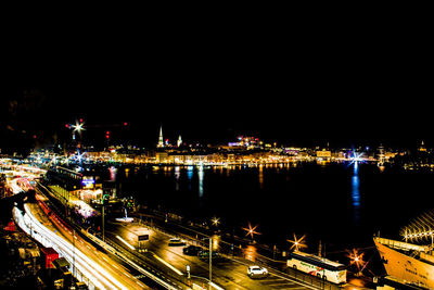 High angle view of illuminated city by buildings at night