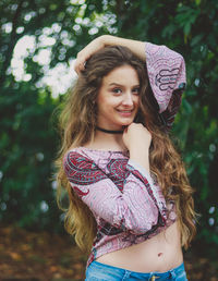 Portrait of smiling beautiful young woman standing against trees