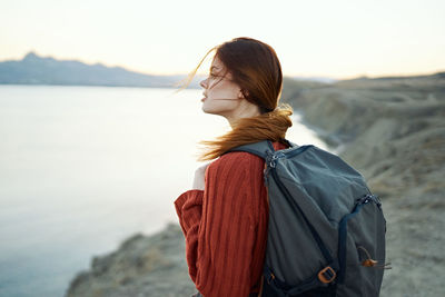 Young woman looking at sea against sky