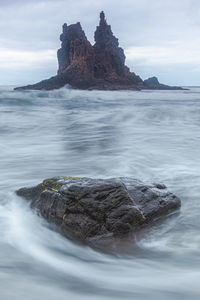 Scenic view of rock formation in sea against sky