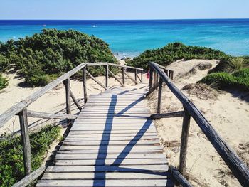 Wooden railing on beach against sky