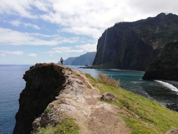 Scenic view of sea by mountains against sky