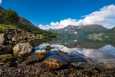 Scenic view of lake and mountains against blue sky