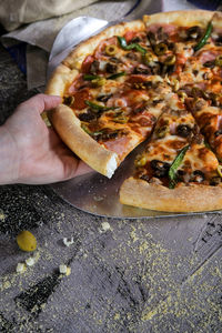 Cropped image of woman hand having pizza at table