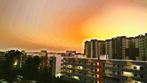 Cityscape against dramatic sky during sunset