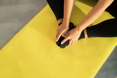 Girl does stretching on yoga mat, her legs are folded in butterfly pose and her hands hold feet 