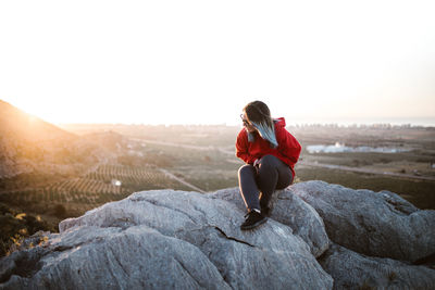 Full length of woman sitting on rock