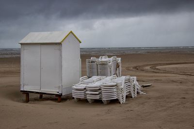 Hooded chairs on beach against sky