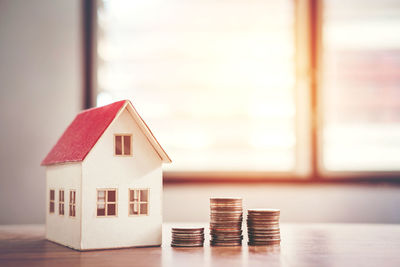 Close-up of model house and stacked coins on table at home