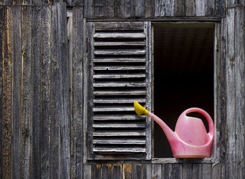 Watering can on the window of wooden house