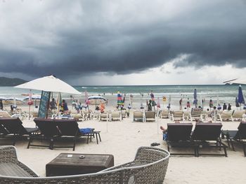 Chairs and tables on beach against sky