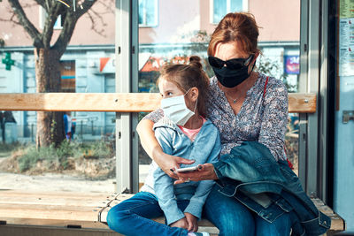 Woman and her child waiting for a bus sitting at bus stop of public transport