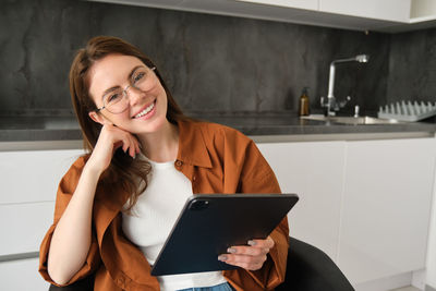 Young woman using mobile phone while sitting at home